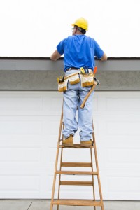 Man on ladder inspecting roof