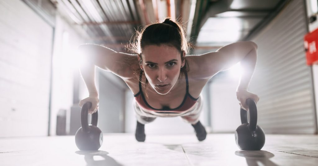 woman doing kettlebell push ups in garage gym
