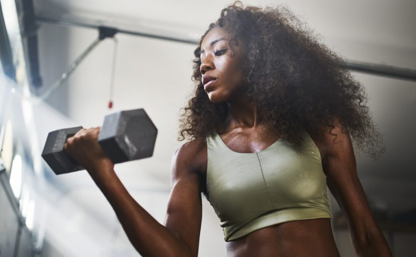 woman in garage gym lifting bar bells